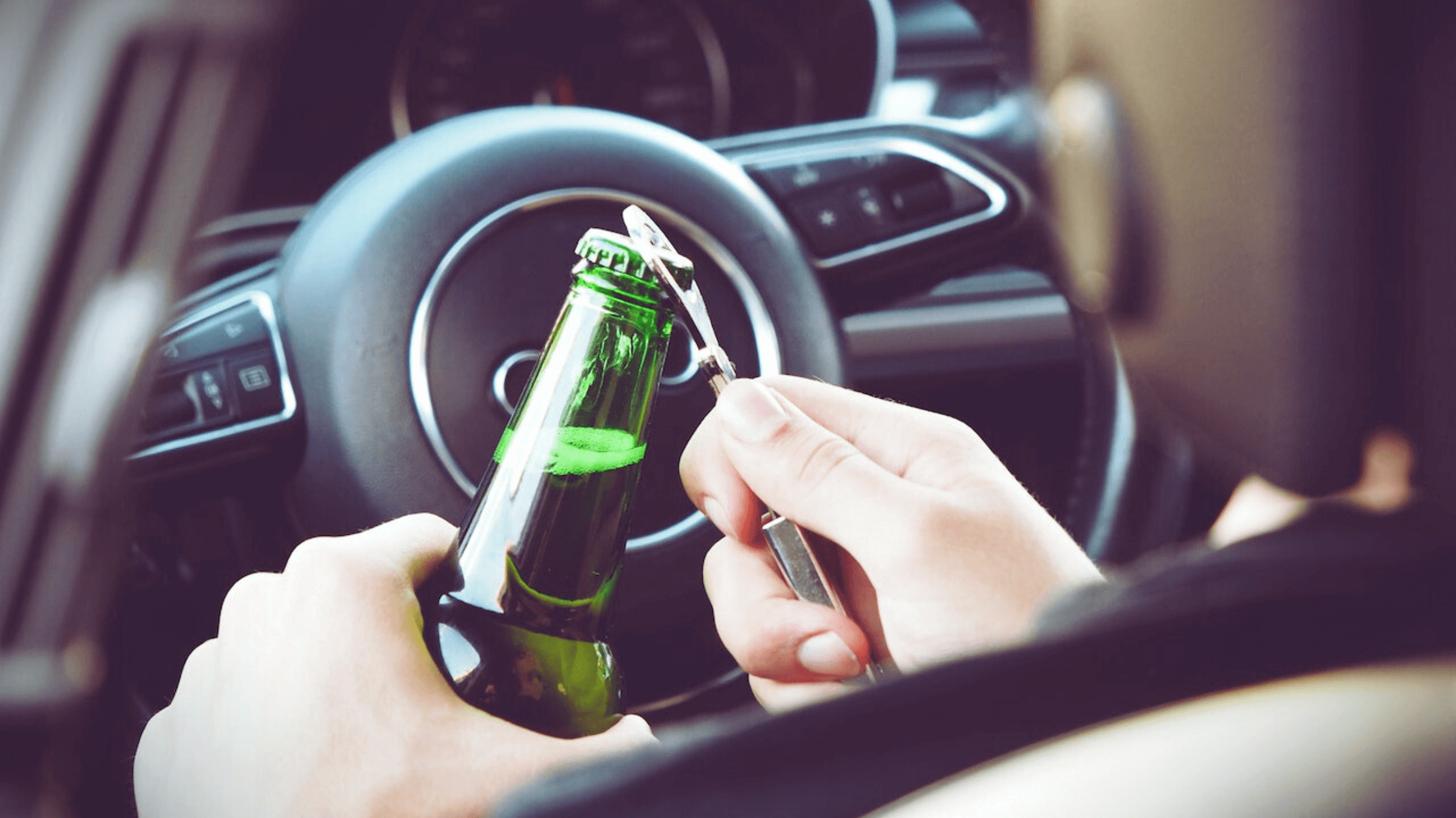 Underage driver opening beer bottle inside a moving car, highlighting DUI risks.