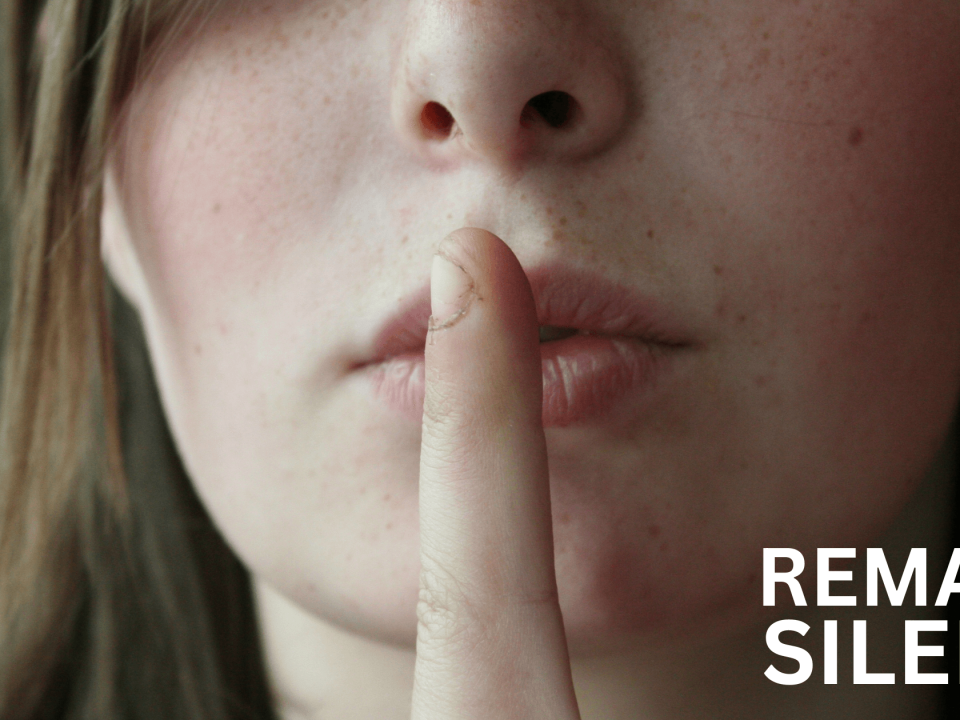 Person with finger on lips signaling silence with bold REMAIN SILENT text.